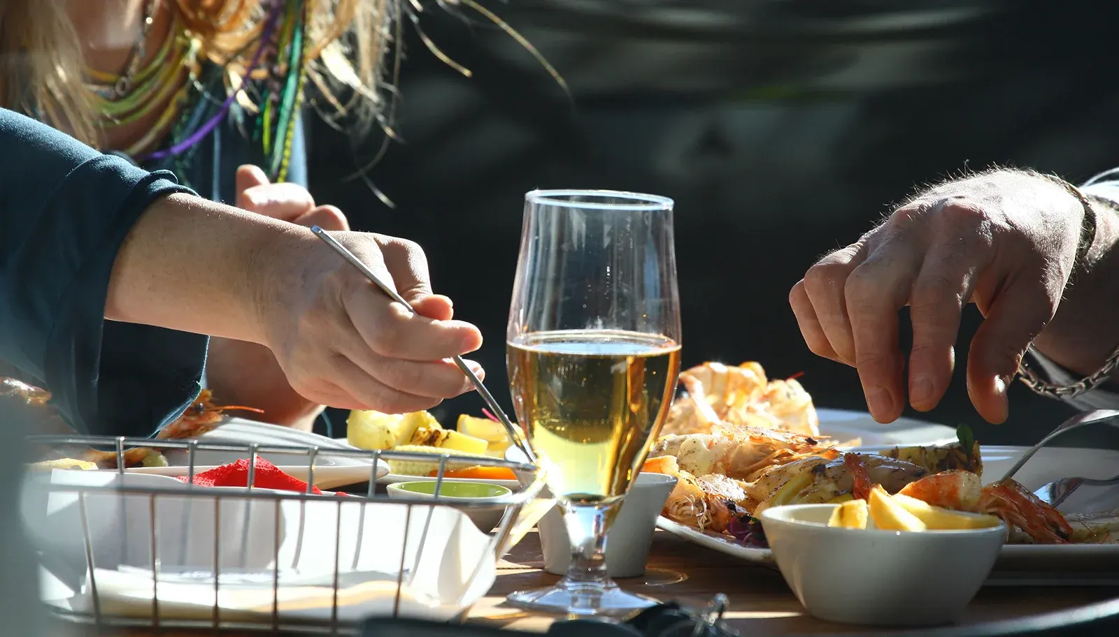 Guests sharing seafood and drinks on the beachfront patio at Café Orca